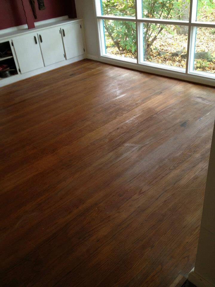 brown and scratched hardwood floors in a red bedroom